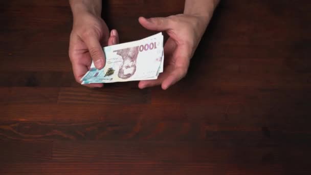 Muž obdržel nové bankovky na pokladně, prohlíží si je a nechá je na dřevěném stole. Nové bankovky ukrajinské národní banky v Hryvnii. Prores 422 — Stock video