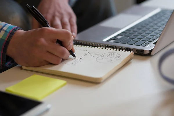 Espaço de trabalho do jovem. Visão de perto de mãos de homens desenho diagrama no caderno — Fotografia de Stock