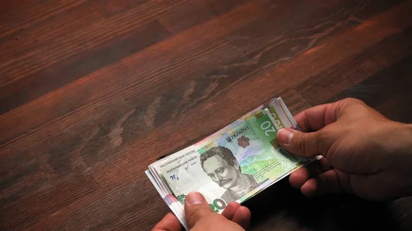 L'uomo che ha ricevuto la pensione o il pagamento alla cassa bancaria, sta rivedendo le nuove banconote. Introduzione di nuovi soldi dalla banca nazionale ucraina. Concetto di cassa. Concetto di investimento — Foto Stock