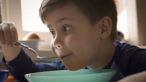 Голодный ребенок ест суп. Мальчик обедает или ужинает в детском саду. Крупный план — стоковое фото