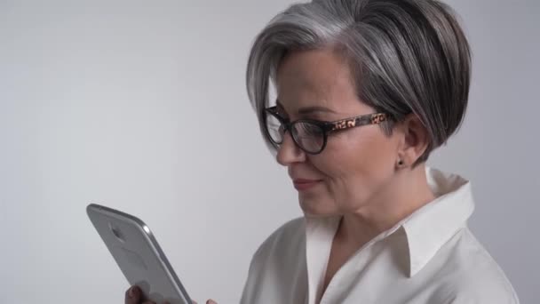 Gråhårig vit affärskvinna skriva på digital tablett på vit bakgrund. Affärs- eller utbildningskoncept. Prores 422 — Stockvideo