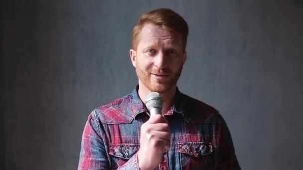 Ginger blogueur gars faire des vidéos à la maison avec micro. Beau jeune homme portant une chemise en jean s'enregistrant lui-même sur vidéo avec microphone. Prores 422 — Video