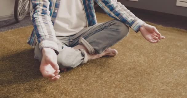 Hipster jovem meditando e relaxando em pose de lótus enquanto sentado no chão com bicicleta. Homem de negócios a fazer uma pausa do trabalho no computador. Trabalho em casa. Prores 422 — Vídeo de Stock