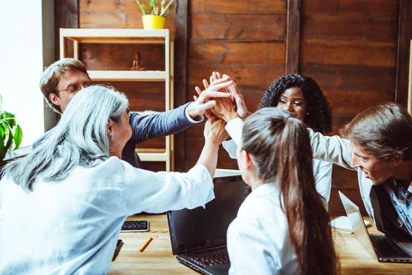 Diverso gruppo che unisce le mani dopo il successo del brainstorming. La squadra di ufficio ha unito mani in unità gioiosamente dando il cinque gesto all'un l'altro. Concetto di lavoro di squadra. Immagine tonica — Foto Stock