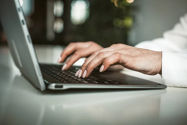Női kezek gépelnek a laptop billentyűzetén az irodában. Üzletasszony, aki számítógéppel dolgozik. Közelről. Színes kép — Stock Fotó