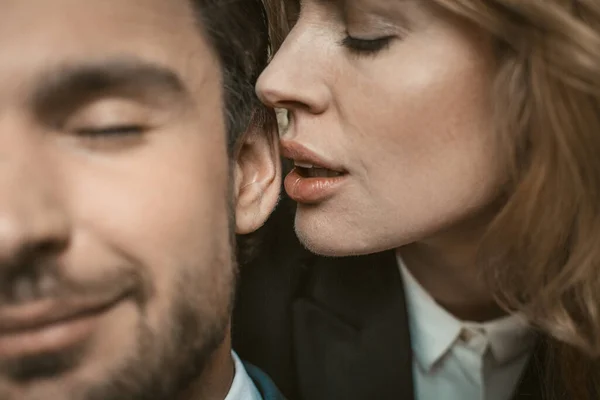 Frau küsst oder flüstert Mann ins Ohr. Selektiver Fokus auf weibliche Lippen in der Nähe des männlichen Ohres in der Bildmitte. Leidenschaftliches verliebtes Paar. Nahaufnahme — Stockfoto