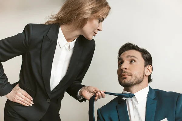 Kadın patron çalışanı baştan çıkarır. İş adamının ceket yakasını tutan yaramaz genç bir iş kadını. Cinsel taciz kavramı — Stok fotoğraf