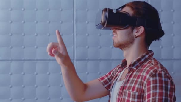 Молодий чоловік в окулярах віртуальної реальності грає в гру, що стоїть збоку. Майбутнє зараз. Красивий чоловік торкається повітря за допомогою сучасних окулярів віртуальної реальності. Пропозиції 422 — стокове відео