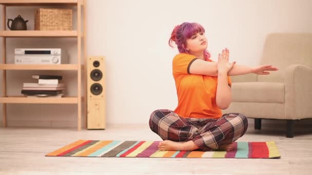 Дівчина, що сидить на підлозі, виконуючи вправи з йоги, в позі лотоса розтягується руками. Концепція надмірної ваги. Концепція здорової їжі. Пропозиції 422 — стокове відео