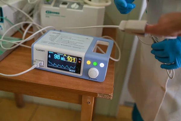 Врач измеряет сердечный ритм и уровень насыщения кислородом в крови пациента. Медицинское оборудование. Человеческая рука с прикрепленным элементом импульсного оксиметра. Городская больница Май, 2020, Бровары, Украина — стоковое фото