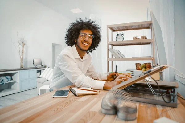 Щасливий молодий арабський чоловік, який працює з ноутбуком вдома. Творчий хлопець дивиться на камеру, усміхаючись. Приборканий образ. Концепція фрілансу. Тонограма — стокове фото