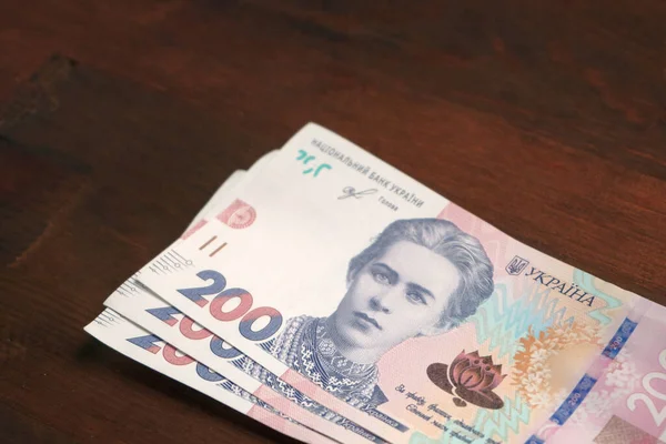 Das neue ukrainische Papiergeld. Zweihundert Hrywnja-Scheine auf braunem Holzgrund. Cash-Konzept. Nahaufnahme — Stockfoto