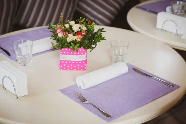 Romantický jídelní stůl s roztomilou květinovou výzdobou a fialovými ubrousky v útulném interiéru. Koncept výročí nebo události — Stock fotografie