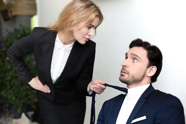 Pretty woman seduces her boss. Caucasian blonde businesswoman holding tie of businessman. Sexual harassment concept — Stock Photo, Image