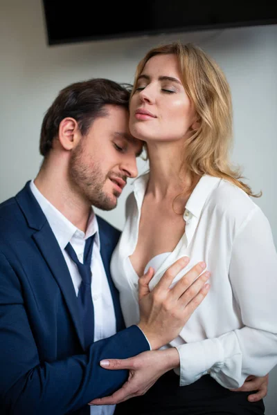 Business people closing eyes with pleasure while flirting in office. Man touching female body. Sexual enjoyment concept. Flirtation or sexual harassment at workplace — Stock Photo, Image