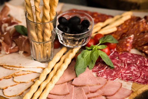 Assorted meat slicing with breadsticks and olive on wooden plank. Close up shot. Holiday or event treats. Catering food concept. Antipasti concept — Stock Photo, Image