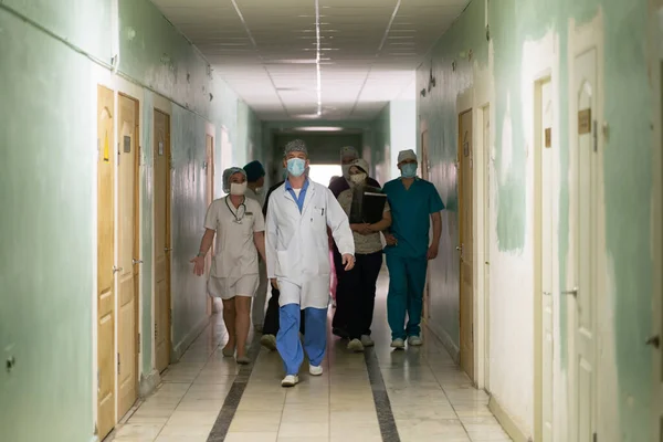 Лікарі йдуть коридором до лікарні. Група професіоналів у білих плащах збирається лікувати пацієнтів. Міська лікарня. Травень 2020, Броварі, Україна — стокове фото
