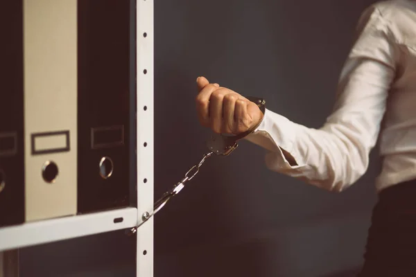 Empresaria encerrada en la oficina. Mano femenina esposada a la estantería de la oficina con carpetas. Bloquee el concepto. Primer plano. Imagen teñida —  Fotos de Stock