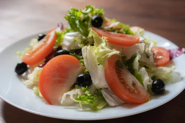 Salada vegetal fresca com tomates e azeitonas. Aperitivo de vitamina natural colorido. Refeição leve de primavera bonita ou refresco no prato branco. Conceito de alimentação saudável. Fechar tiro — Fotografia de Stock