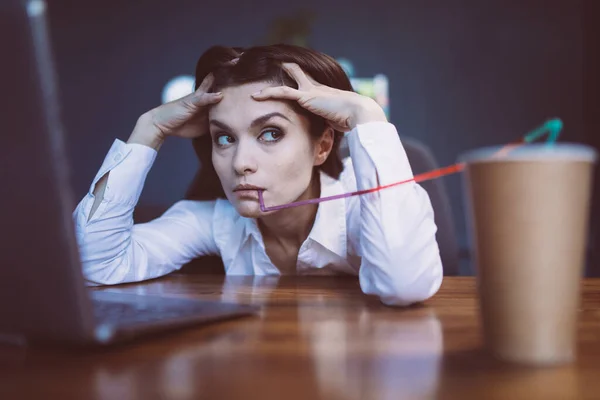 Femme d'affaires ennuyée boit du café. Jeune fille ennuyeuse sur le lieu de travail avec un lapin dessus tout en regardant côté. Concept de crise. Image teintée — Photo