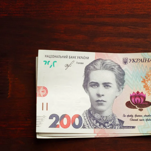 Новые украинские банкноты 200 гривен. Красивая известная женщина на бумажных деньгах. Изолированный на деревянном фоне. Концепция денежных средств. Крупный план. Тонированное изображение — стоковое фото