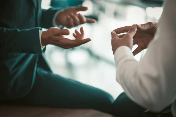 Duas pessoas de negócios conversam sentado na mesa do escritório. Feche o tiro de mãos de funcionários de escritório. Imagem matizada — Fotografia de Stock