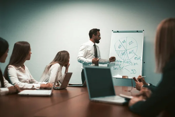 Equipe de negócios na apresentação na sala de reuniões do escritório. Falando empresário mostra gráfico de torta apontando no quadro branco. Imagem matizada — Fotografia de Stock