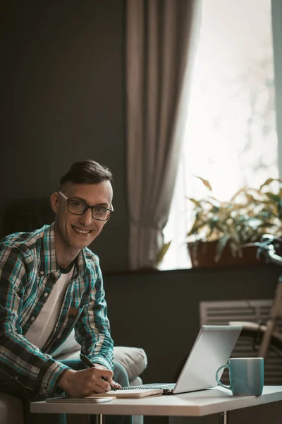 Jovem freelancer trabalhando em casa durante o dia. Masculino trabalhando com laptop em casa interior — Fotografia de Stock