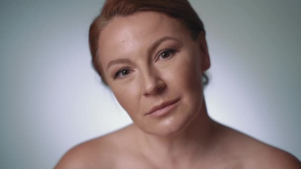 Das weibliche Model mittleren Alters posiert in einem Fotostudio. weißer Hintergrund. Lächelndes Gesicht — Stockvideo