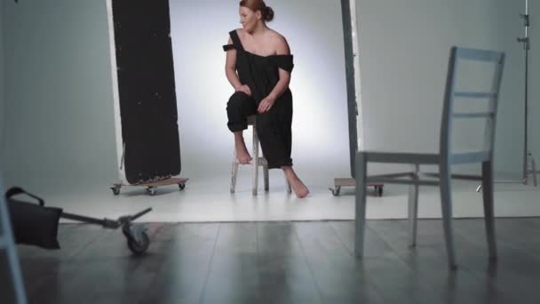 Uśmiechnięta kobieta w średnim wieku, pozująca w czarnej sukience. Fotografowanie modelki w studiu fotograficznym . — Wideo stockowe