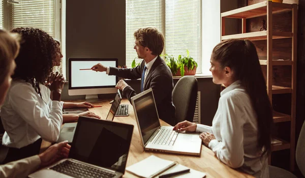 Présentation du projet. Homme d'affaires pointe vers l'écran blanc de moniteur d'ordinateur lors de la réunion de la jeune équipe au bureau. Concept de diversité ethnique. Image teintée — Photo