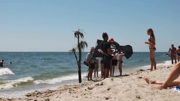 Kumsalda para için hayvanlarla çekim yapmak. Deniz kenarına, plaja. Papağan ve korsan bayrağı olan bir adam fotoğraf servisi sunuyor. Deniz konseptiyle kumsalda dinlenmek. Yüksek kalite 4K görüntü. 3 Ağustos 2020 — Stok video
