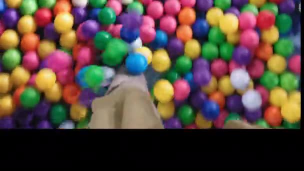 Der Mensch läuft auf farbigen Plastikbällen. Pool mit bunten Kugeln. . Hochwertiges 4k Filmmaterial. HUAWEI MATE 20 X — Stockvideo