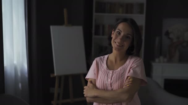 Kobieta w średnim wieku z krótkimi brązowymi włosami uśmiecha się do kamery stojąc w mieszkaniu. Koncepcja emocji. — Wideo stockowe