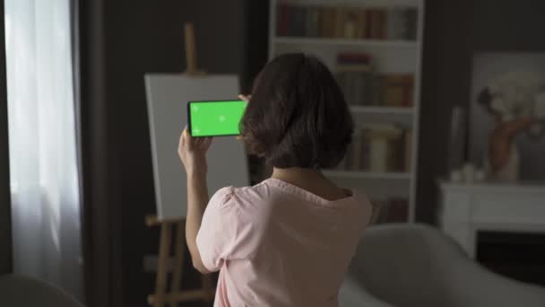 Középkorú nő beszél telefonon videochat-en keresztül. Otthon videózunk. Karantén koncepció.Telefon zöld háttérrel. Vízszintes. — Stock videók