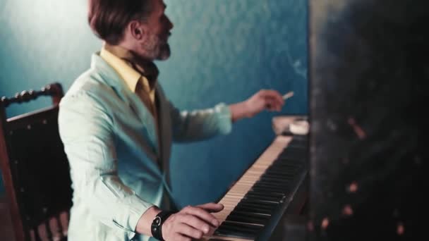 Ένας ελκυστικός μουσικός με γενειάδα παίζει πιάνο. Ο άνθρωπος πίσω από ένα μουσικό όργανο με ένα τσιγάρο στο στόμα. Παίζει ακόρντα και καπνίζει. Υψηλής ποιότητας FullHD footag — Αρχείο Βίντεο