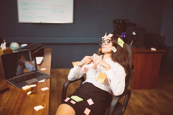 Joven empresaria cansada con tarjetas de notas pegadas. Dama caucásica pensativa sentada en el sillón en la oficina. Vista lateral. Concepto multitarea. Imagen teñida —  Fotos de Stock