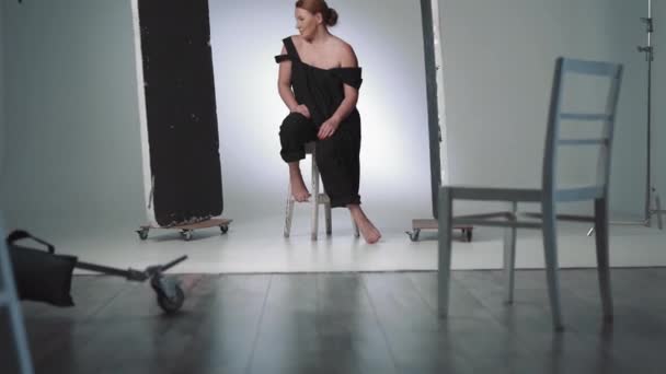 Улыбающаяся женщина средних лет в черном платье. Модель позирует в фотостудии. — стоковое видео