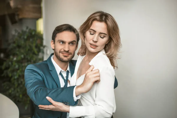 Colleague undresses an office worker at a desk. He unbuttons her blouse. Workplace romance concept. High quality photo — Stock Photo, Image