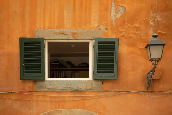 Opened window with green shutters on orange wall of old building — Stock Photo, Image