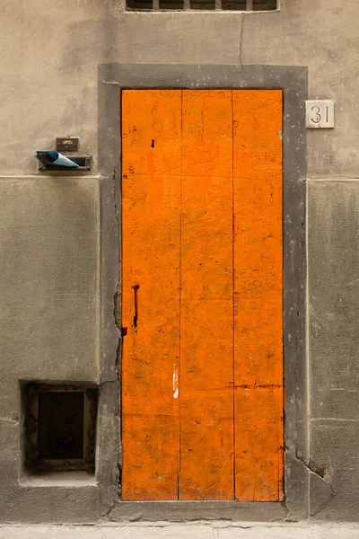 Wooden front door and house number 31 on old wall. Orange door on gray background — Stock Photo, Image