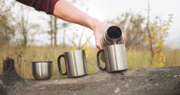 白人在杯子里倒茶.两个人在自然界。森林漫步。秋季受孕积极休市日 — 图库视频影像