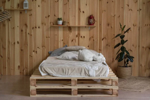 Cama de madeira em estilo simples. Interior é feito de madeira. Linho claro. Prateleiras de vasos. Foto de alta qualidade — Fotografia de Stock