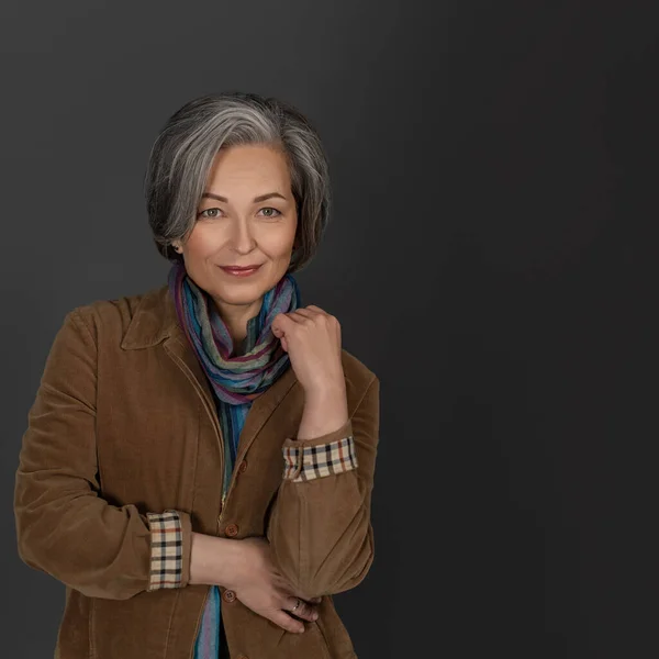 Mulher de meia-idade bonita em posar casual no fundo da parede cinza em estúdio. Retrato de mulher bonita — Fotografia de Stock
