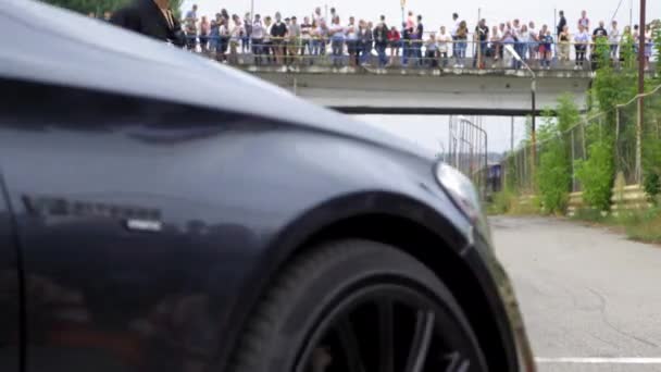 Sötét Mercedes elhajt a rajtvonalig a pályán. Kilátás hátulról. A háttérben nézők állnak a hídon. 2020. augusztus 24. Kijev, Ukrajna — Stock videók