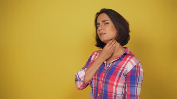 Ung kvinna får ont i halsen av en förkylning, hon hostar. Brunett tvättar halsen med fingrarna och täcker munnen med handen medan hon hostar. Hög kvalitet — Stockvideo