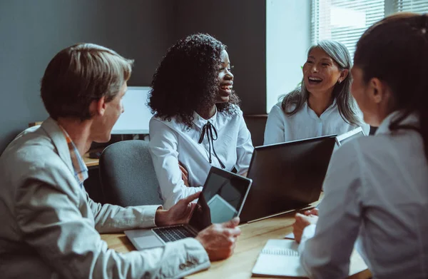 Une équipe diversifiée passe un drôle de moment à une réunion d'affaires au bureau. Mes collègues rient et discutent des moments de travail. Photo de haute qualité — Photo