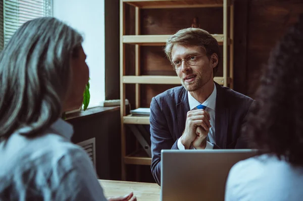 Equipo de intercambio de ideas del personal de la oficina. El hombre con gafas tiene una discusión con sus colegas en su escritorio. Foto de alta calidad — Foto de Stock