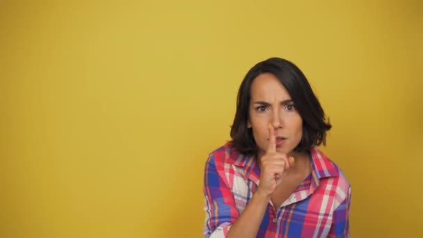 Ung kvinna ber aggressivt att vara tystare med en gest. Brunett sätter fingret på läpparna och väser. Hög kvalitet — Stockvideo