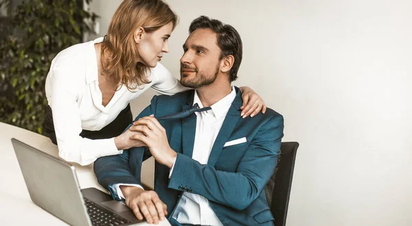 Bizneswoman uwodzi pracownika biurowego siedzącego przy biurku. Kobieta ciągnie faceta za krawat. Uwodzenie podwładnego w biurze. Skopiuj miejsce po prawej stronie. Wysokiej jakości zdjęcie — Zdjęcie stockowe